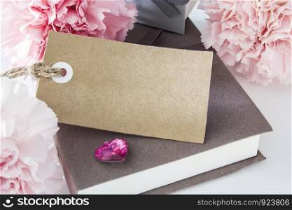 Blank paper tag with gift box and carnation flowers
