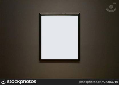 Blank picture frame hanging on black wall - framed poster mockup with dark wall background