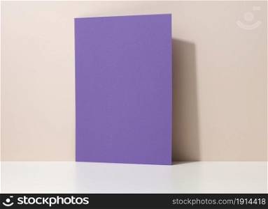 blank purple cardboard sheet of paper with shadow on white table. Template for flyer, announcement