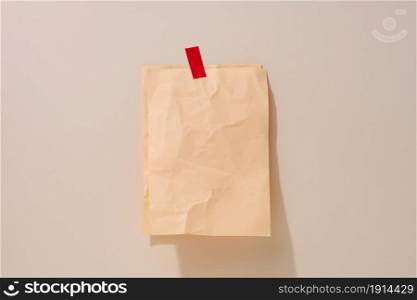 blank rectangular crumpled beige sheet of paper glued on a light beige background. Place for an inscription, announcement