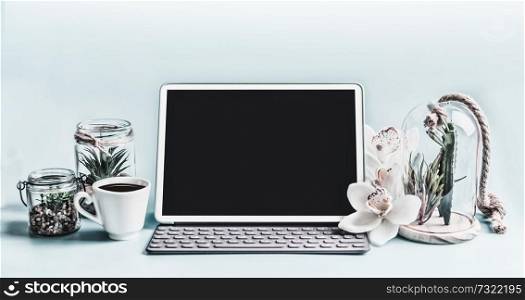 Blank screen modern laptop computer with succulent plants in glasses and orchid flowers on table.  Home female business office workspace.  Black blank screen for your design