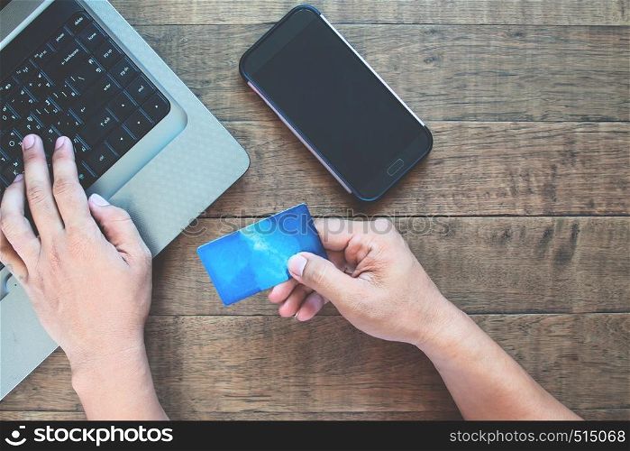 Blank screen smartphone for application mock up with man using credit card and laptop computer