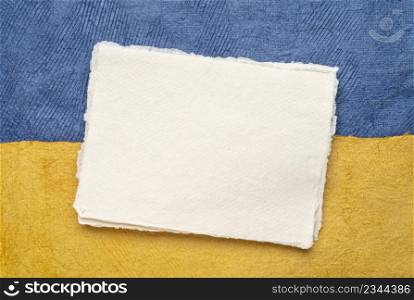 blank sheet of handmade paper against abstract in colors of Ukrainian national flag - blue and yellow