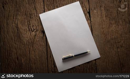 Blank sheet of paper and pen on wooden table.. Blank sheet of paper and pen on wooden table.