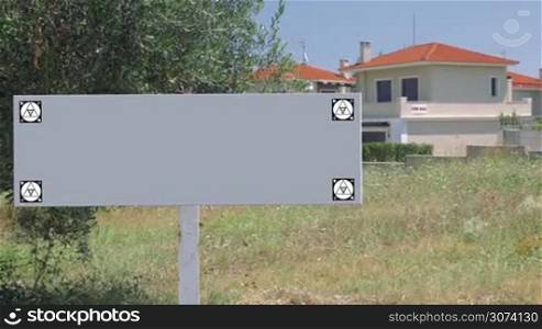 Blank signboard with house for sale in background. Copy space for real estate advertising. Chroma key with tracking motion markers