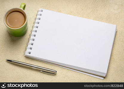 blank spiral art sketchbook against against textured bark paper with a cup of coffee