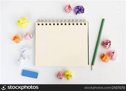 blank spiral diary surrounded by crumpled paper with pencil eraser