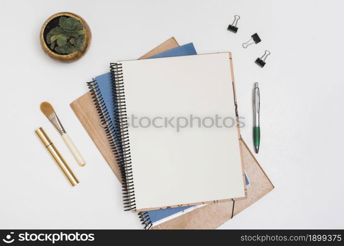 blank spiral note with make up brush mascara paper clips pen with potted plant white desk. Resolution and high quality beautiful photo. blank spiral note with make up brush mascara paper clips pen with potted plant white desk. High quality beautiful photo concept