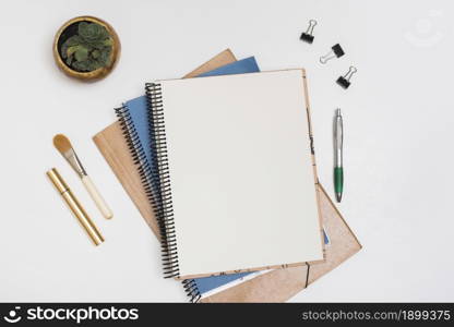 blank spiral note with make up brush mascara paper clips pen with potted plant white desk. Resolution and high quality beautiful photo. blank spiral note with make up brush mascara paper clips pen with potted plant white desk. High quality beautiful photo concept