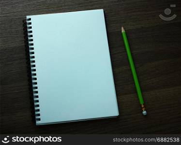 blank spiral notebook and pencil on dark wood background