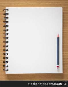 blank spiral notebook and pencil on wood background