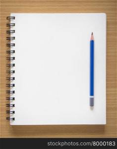 blank spiral notebook and pencil on wood background