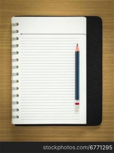 blank spiral notepad and pencil on wood background