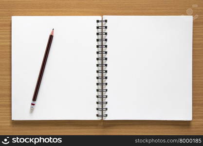 blank spiral notepad and pencil on wood background