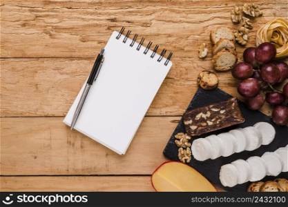 blank spiral notepad with ballpoint pen near raw ingredients textured background