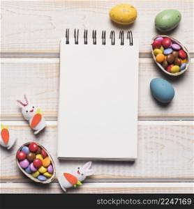 blank spiral notepad with colorful gems easter eggs white bunnies wooden desk