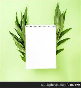 blank spiral notepad with leaves side green background