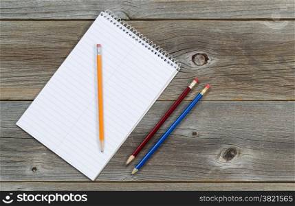 Blank spiral notepad with pencils on rustic wooden boards