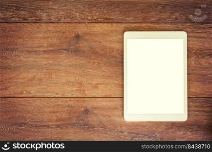 Blank Tablet computer on wood table background with space for text.