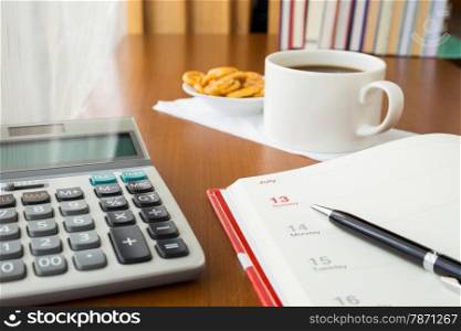 Blank timetable or calendar place on table with calculator and coffee break