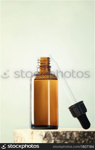 Blank transparent amber glass essential oil bottle with pipette on wooden slice podium, Beauty blog, salon treatment concept