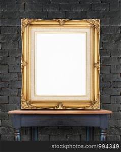 Blank vintage golden photo frame lean at black brick wall on wood table,Template Mockup for add picture.
