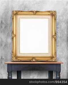 Blank vintage golden photo frame lean at gray color concrete wall on wood table,Template Mockup for add picture..