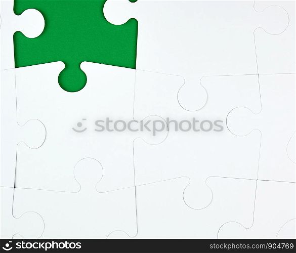 blank white big puzzles on green background, copy space, one element of the puzzle is missing