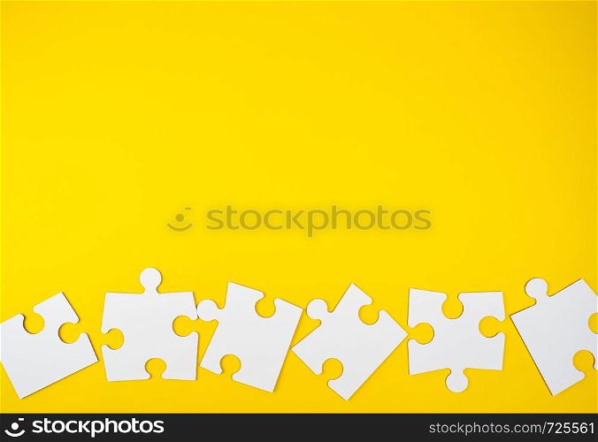 blank white big puzzles on yellow background, flat lay, copy space