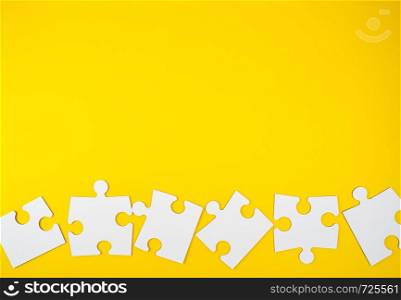 blank white big puzzles on yellow background, flat lay, copy space