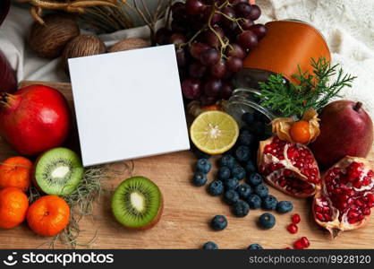 Blank white box packaging among colourful fruits, berries, kiwi, pomegranate and citrus. Dietary supplement packaging box.