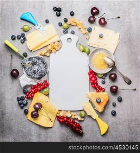Blank white cutting board and various cheese with knife ,berries and honey, top view, frame