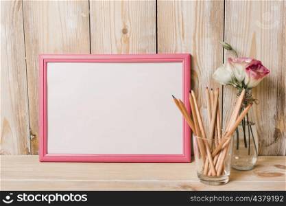blank white frame with pink border colored pencils glass wooden desk