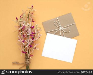 Blank white greeting card with orchis flowers bouquet on yellow background, minimal style.