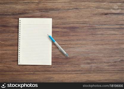 Blank white notebook pad on wood desk background with copy space. Top down
