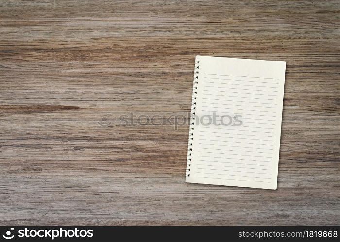 Blank white notebook pad on wood desk background with copy space. Top down