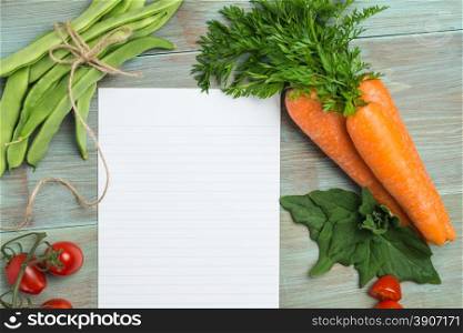 Blank white paper and fresh colorful vegetables on kitchen table