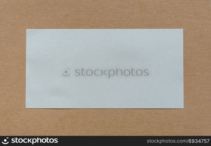 Blank white paper label on brown cardboad background