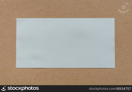 Blank white paper label on brown cardboad background