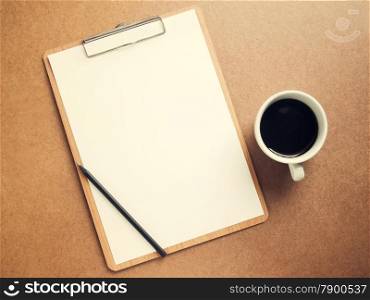Blank white paper on clipboard with cup of coffee, retro filter effect