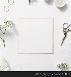 blank white paper surrounded with rings gypsophila string candles scissor white background