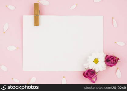 blank white paper with clothespin flowers pink background