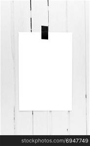 Blank white poster hanging on a tape on white wooden plank wall. Template background for your design.. Blank white poster hanging on a tape on white wooden plank wall.