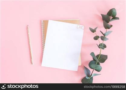 Blank white sheet on spiral golden notepad with paper clip heart, pencil and green branch of eucalyptus on pink pastel background. Mock up for your text and design. Top view Flat lay.. Blank white sheet on spiral golden notepad with paper clip heart, pencil and green branch of eucalyptus on pink pastel background. Mock up for your text and design. Top view Flat lay