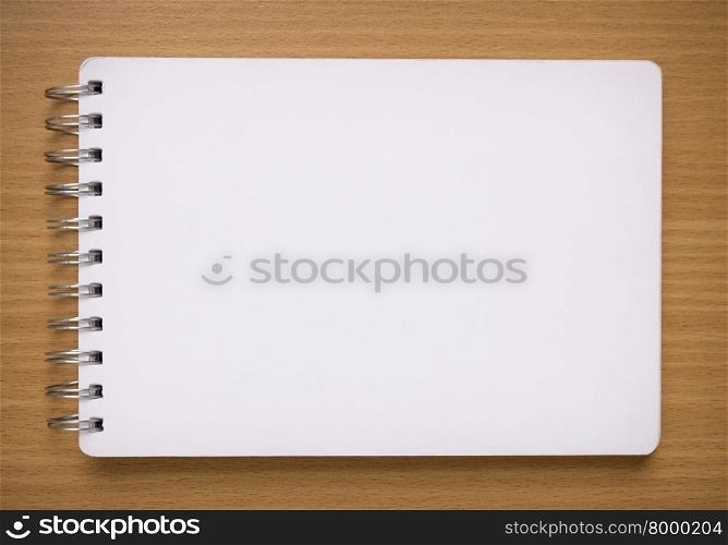 blank white spiral notebook on wood background