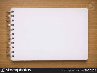 blank white spiral notebook on wood background