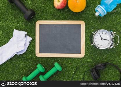 blank wooden slate with sport equipments healthy fruits green turf