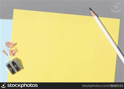 Blank yellow sheet paper, white pencil and sharpener on gray Background. Creative Mock up template flat lay desk