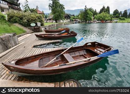 Bled, Slovenia - May 21, 2018: Beautiful Lake Bled in the Julian Alps and two old wooden boats. Mountains, clear aquamarine water, tourist boats, lake and dramatic blue sky.. Beautiful Lake Bled in the Julian Alps and two old wooden boats. Mountains, clear aquamarine water, tourist boat, lake and dramatic blue sky.