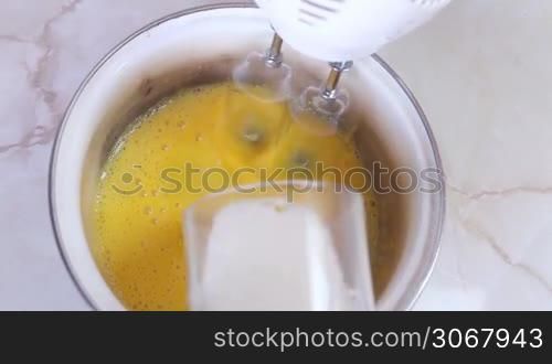 blending egg yolks and sugar with help of modern mixer, closeup